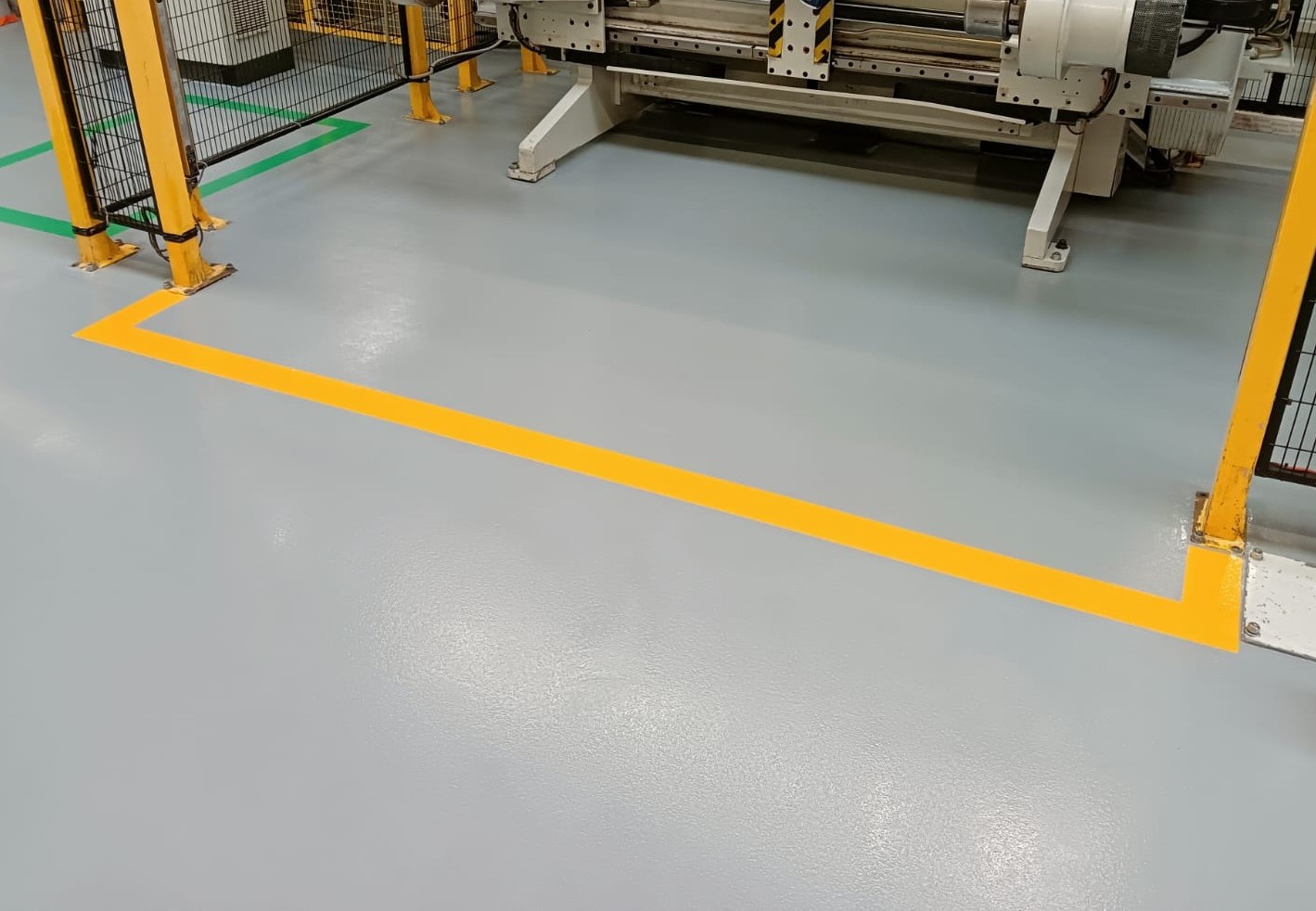 area macchine presso gruppo multinazionale Amcor: pavimenti in resina ESD con bandelle di rame annegate e segnaletica gialla e verde dedicata a lunga durata