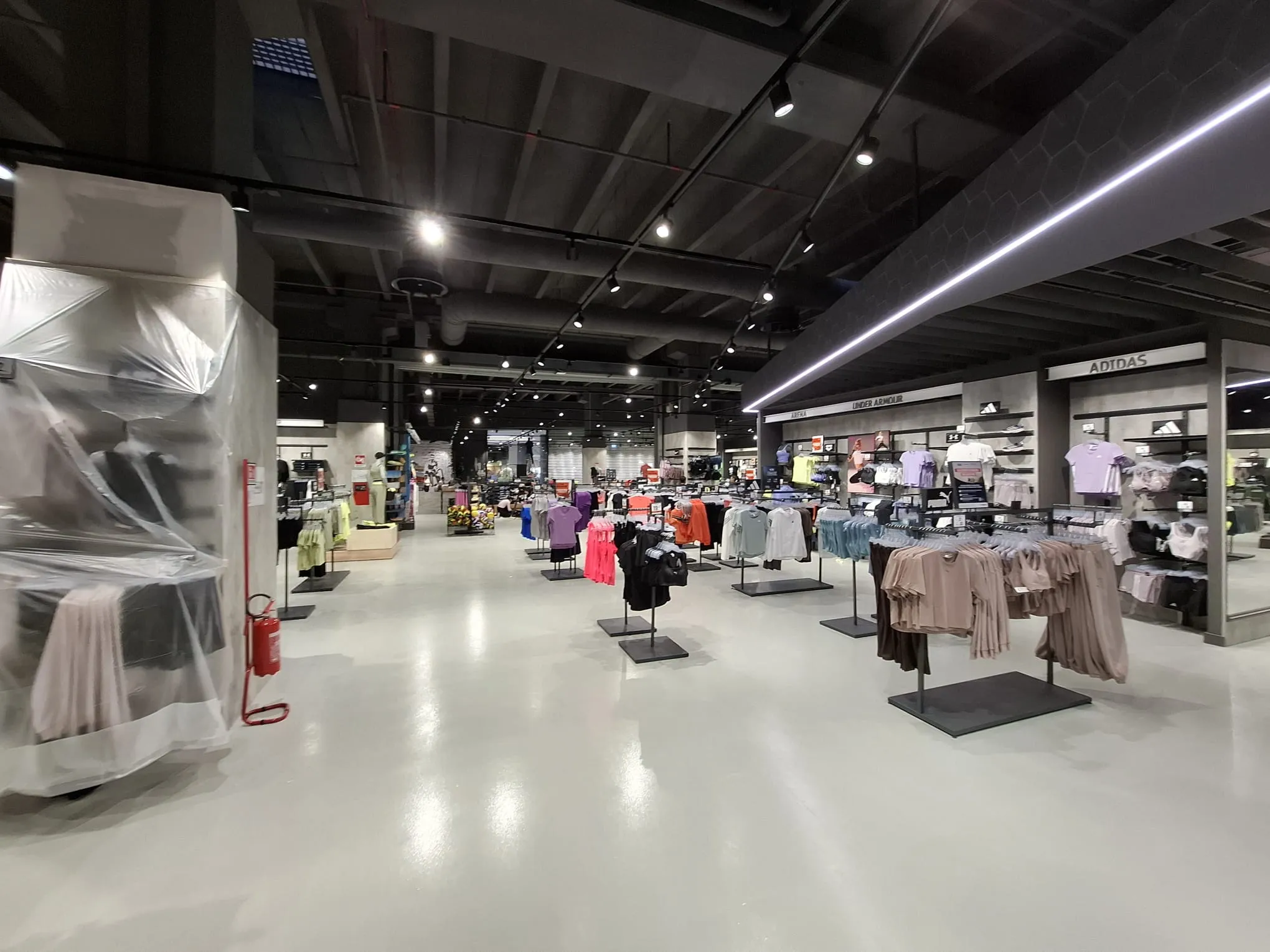 Pavimento in resina epossidica lucida area abbigliamento Cisalfa Sport - Fass Shopping Centre Cagliari - copertura arredi con teli PVC